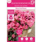 Rhododendron 'Wine and Roses' in bloom with pink flowers and green-red leaves, in a wicker basket, labeled as a winterharde and wintergroene plant.